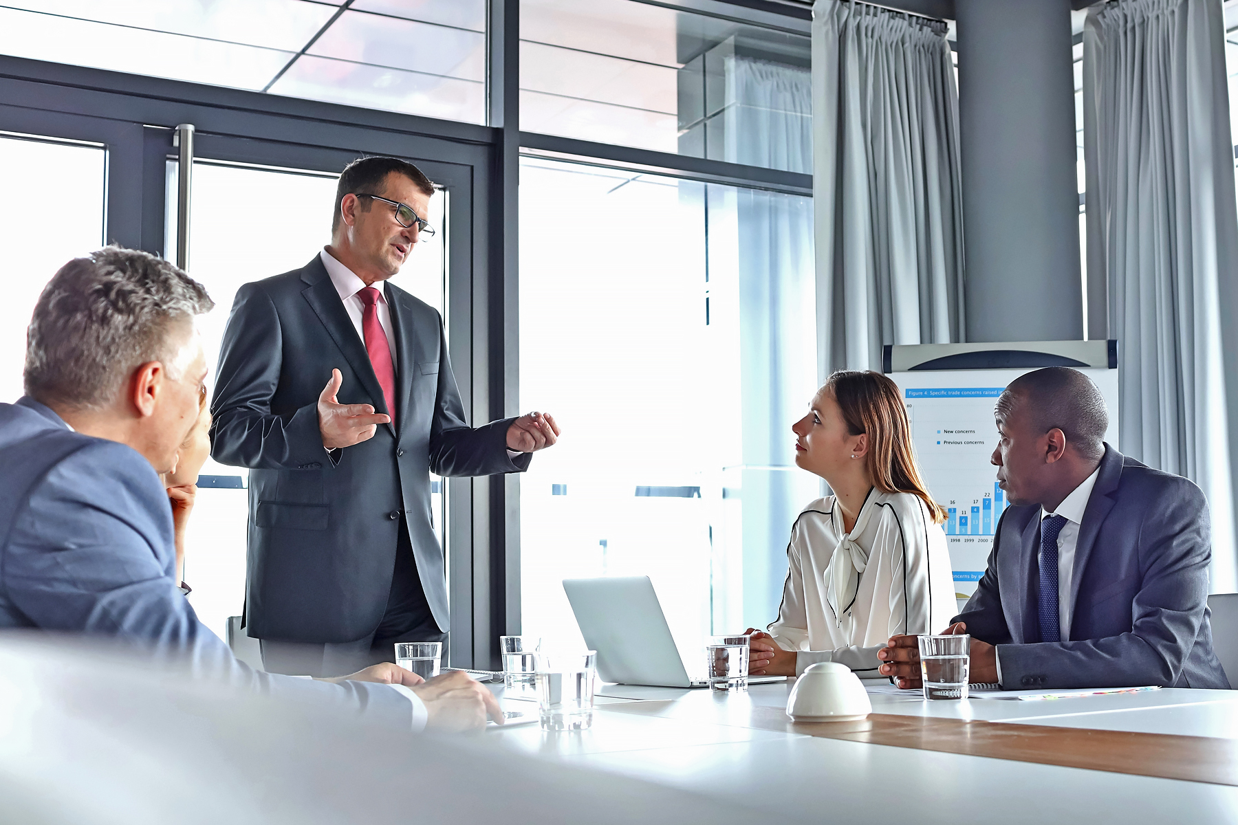 Standing man presenting to four seated individuals.