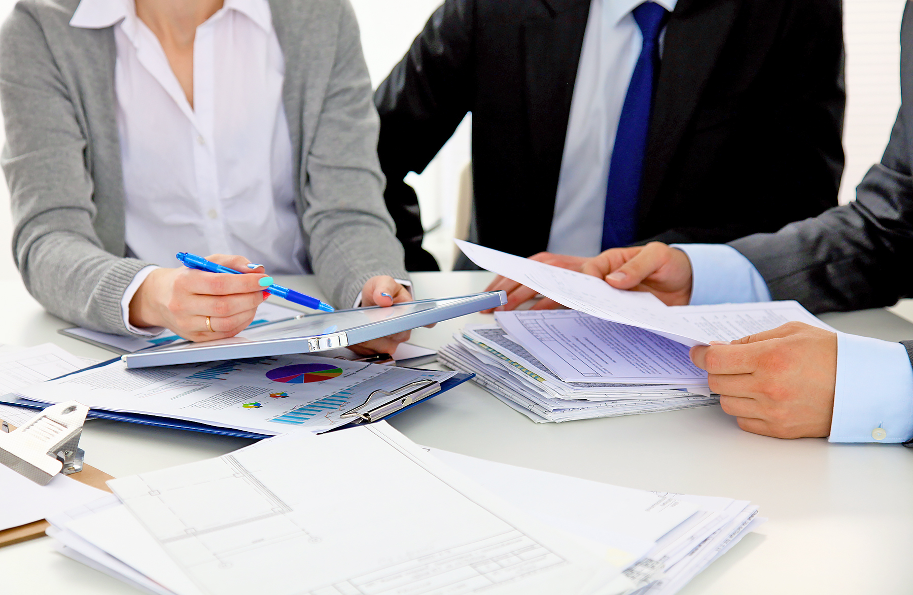 Torso shot of female and two men discussing documents at a table.