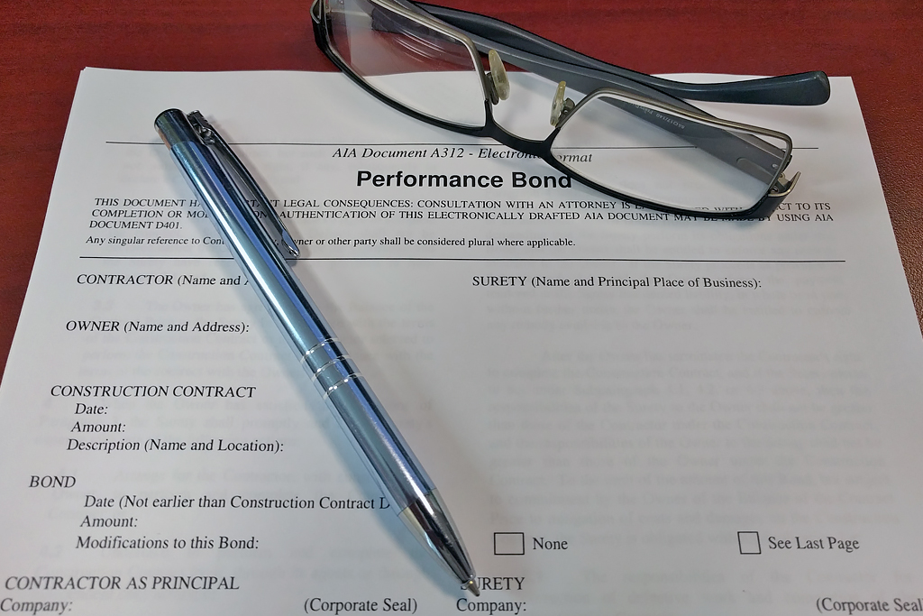 Pen and glasses laying over Performance Bonds document.